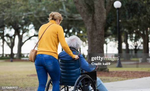 hogere spaanse mens in rolstoel, met volwassen dochter - duwen stockfoto's en -beelden
