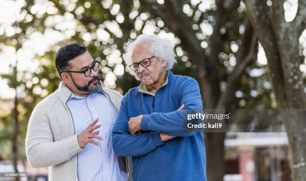 Senior Hispanic Mann Stirnrunzeln als erwachsener Sohn spricht