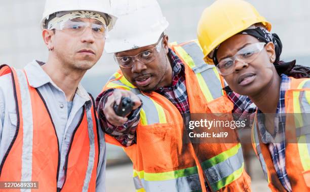 three construction workers in hardhats and safety vests - directing stock pictures, royalty-free photos & images