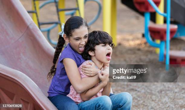 hispanic girl and brother on playground slide - sibling stock pictures, royalty-free photos & images
