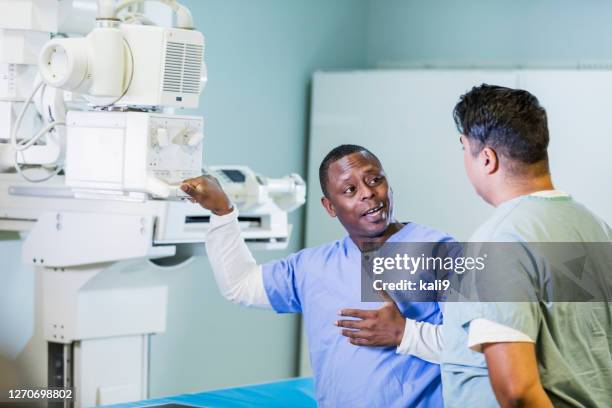 technologists with x-ray equipment, conversing - x-ray technician stock pictures, royalty-free photos & images