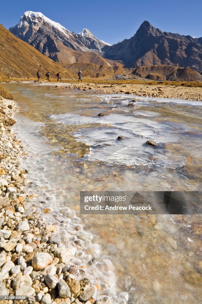 Four Hikers Skirt The Edge Of A Frozen Stream Near Gokyo Nepal High-Res ...