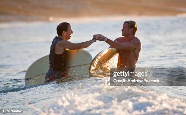 two men share a bonding moment while surfing at t-tree point, noosa heads, queensland, australia. - happy handshake stock pictures, royalty-free photos & images