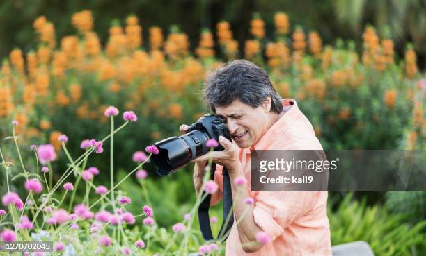 senior hispanic man taking photos in garden - digital camera stock pictures, royalty-free photos & images