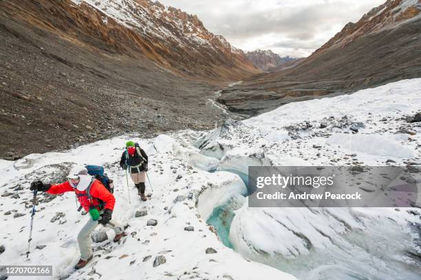 a man and a woman are hiking on snow and ice in spiti, india. - ラホール ストックフォトと画像