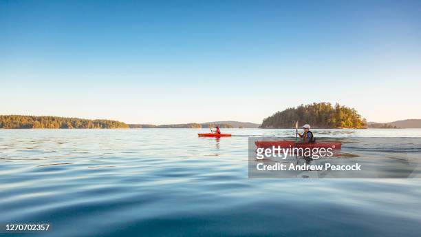 a woman and a boy are kayaking in deer harbor, orcas island, washington, usa - 手漕ぎ船 ストックフォトと画像