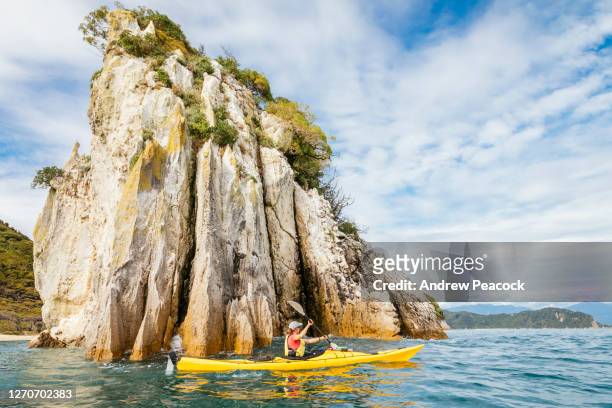 woman kayaking beside abel tasman national park cliffs - tasman stock pictures, royalty-free photos & images
