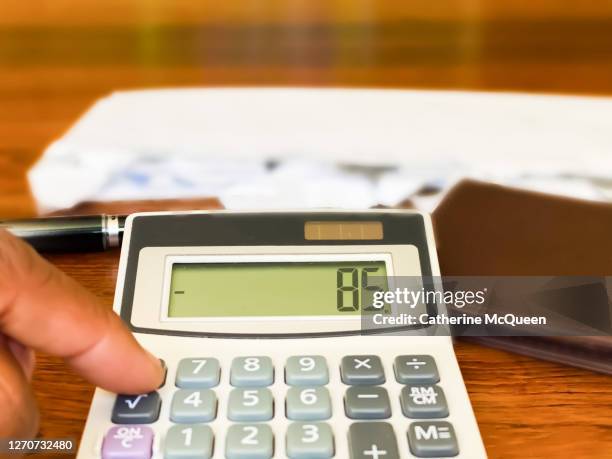 african-american female uses a calculator showing a negative balance while paying monthly bills - unemployment benefits stock pictures, royalty-free photos & images