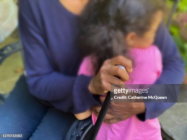 african-american woman hugging mixed-race toddler while sitting & holding walking cane - grandma cane stock pictures, royalty-free photos & images