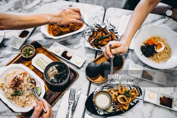 directly above view of family/friends enjoying bonding time having meal together, sharing a variety of freshly served dishes in the restaurant - logement social stockfoto's en -beelden