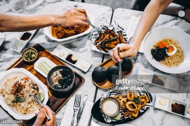 directly above view of family/friends enjoying bonding time having meal together, sharing a variety of freshly served dishes in the restaurant - bangkok hotel stock pictures, royalty-free photos & images