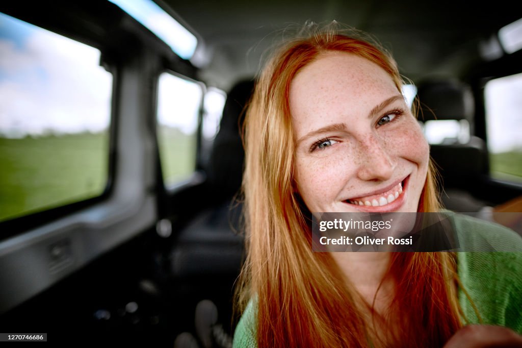 Portrait of smiling redheaded young woman in car