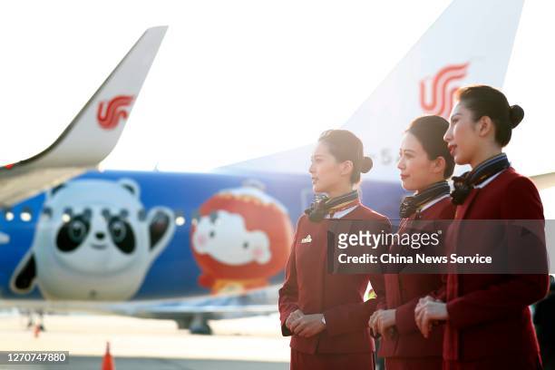 Crew members pose in front of a newly painted Boeing 737 aircraft of Air China with patterns of the emblems and mascots of Beijing 2022 Winter...