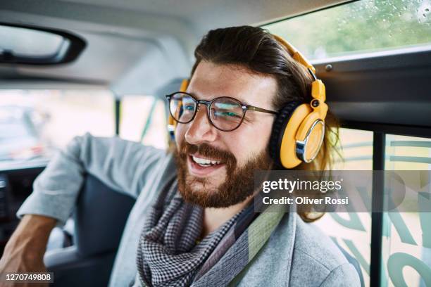 happy bearded man in car wearing hedphones - car listening to music stock-fotos und bilder