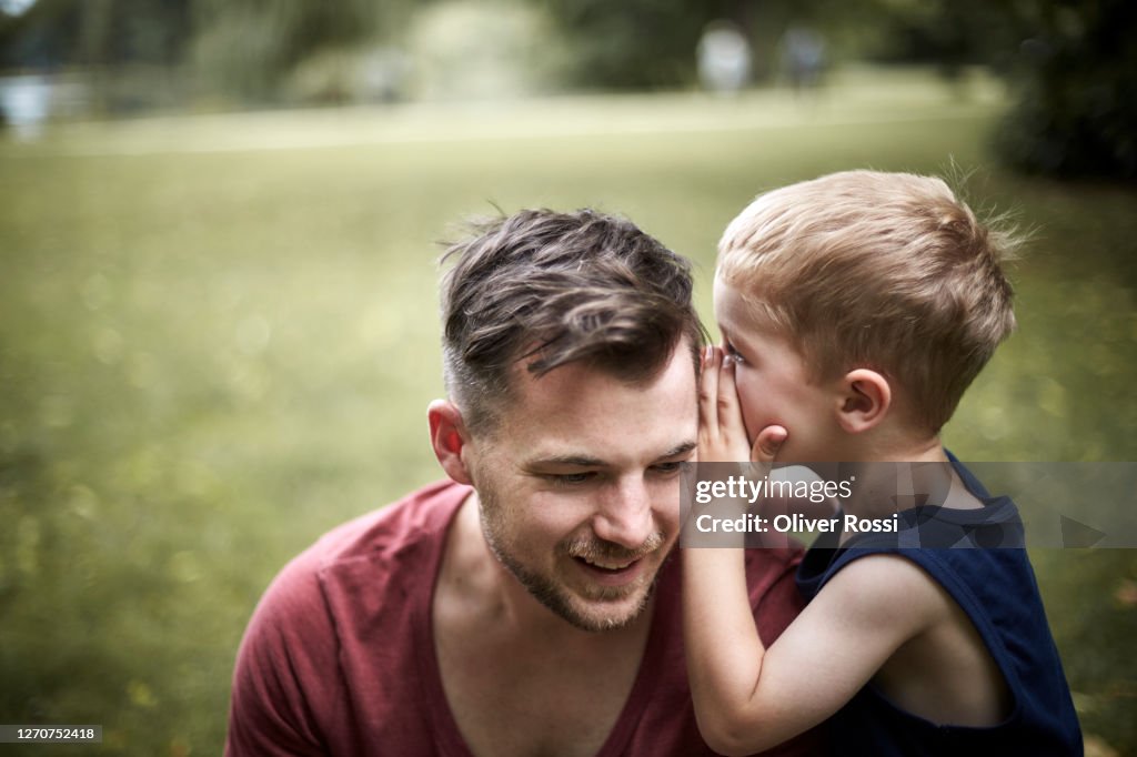 Son whispering into father's ear