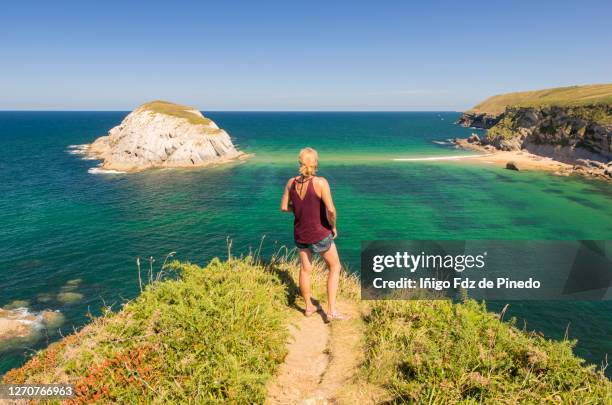 woman admiring a beach of costa quebrada geological park, liencres, spain. - cantabria stock-fotos und bilder