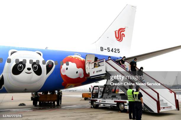 Passengers step off a newly painted Boeing 737 aircraft of Air China with patterns of the emblems and mascots of Beijing 2022 Winter Olympics at...