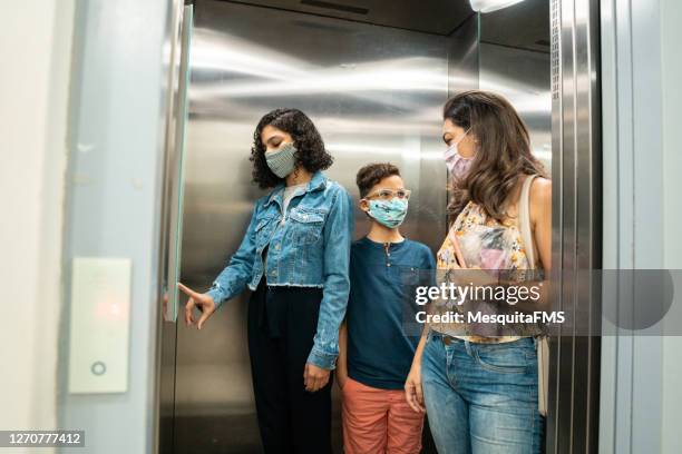 family wearing protective mask in the elevator - social distancing elevator stock pictures, royalty-free photos & images
