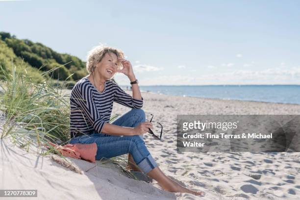 pretty woman sitting on the beach and enjoying the sun. - activities in the sun stock-fotos und bilder