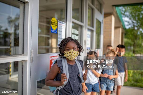 diverse group of elementary school kids go back to school wearing masks - education stock pictures, royalty-free photos & images