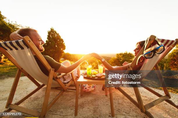 young couple enjoying summer day on deck chairs with cocktails and inflatables - blue curacao stock pictures, royalty-free photos & images