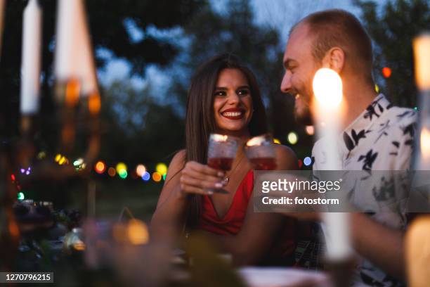 jong paar dat een romantisch diner in hun binnenplaats heeft - tafel voor twee stockfoto's en -beelden