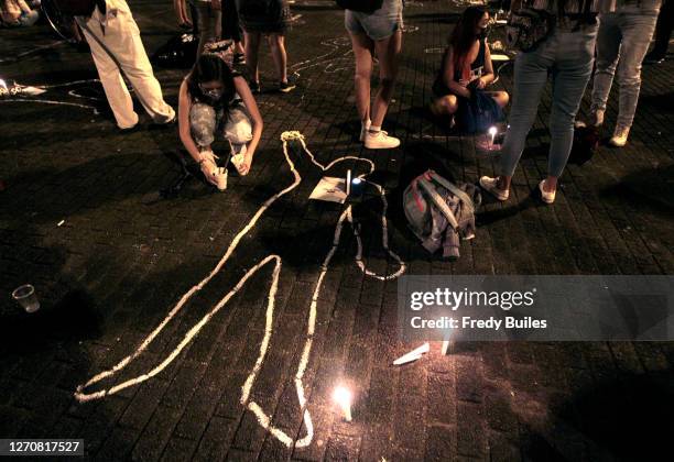 Demonstrator lights a candle during a protest to demand President Ivan Duque action to stop murders of human rights activists, indigenous people,...