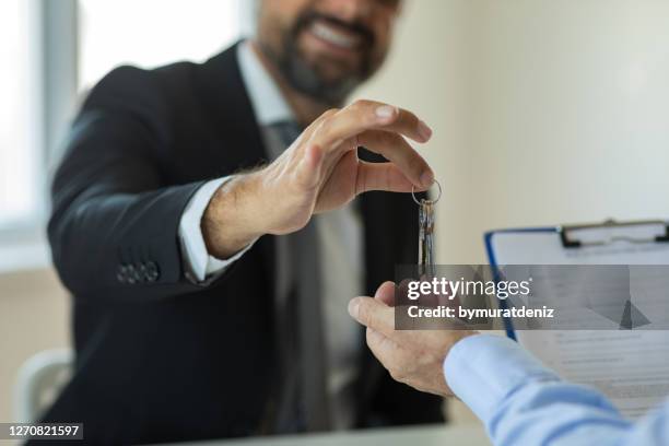 real estate agent hand giving keys to new house owner - contrato de arrendamento imagens e fotografias de stock