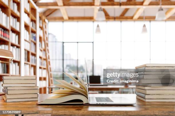 boek en laptop openen in bibliotheek - wisdom knowledge modern stockfoto's en -beelden