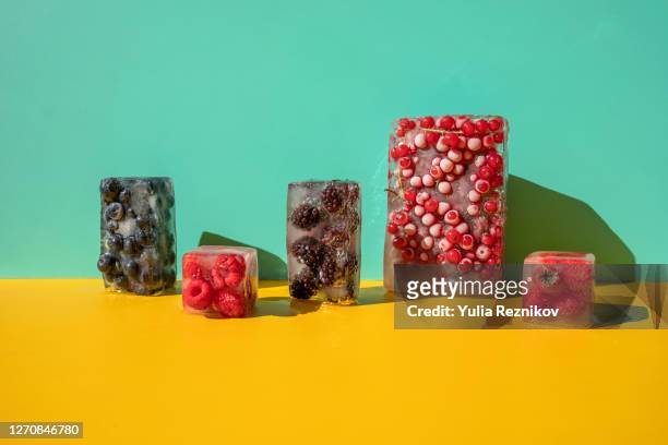 frozen berries on the yellow-blue background - acqua ghiacciata foto e immagini stock