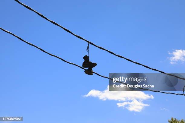 pair of shoes hanging on an electrical wire - untied shoelace stock pictures, royalty-free photos & images