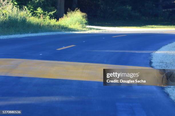speed bump painted high visible yellow colored in the road - speed bump foto e immagini stock