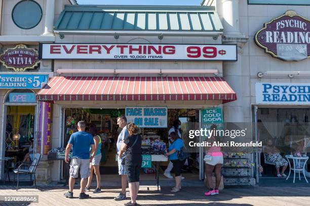 People stand outside an "everything 99 cents" store on the boardwalk as the state of New Jersey continues Stage 2 of re-opening following...