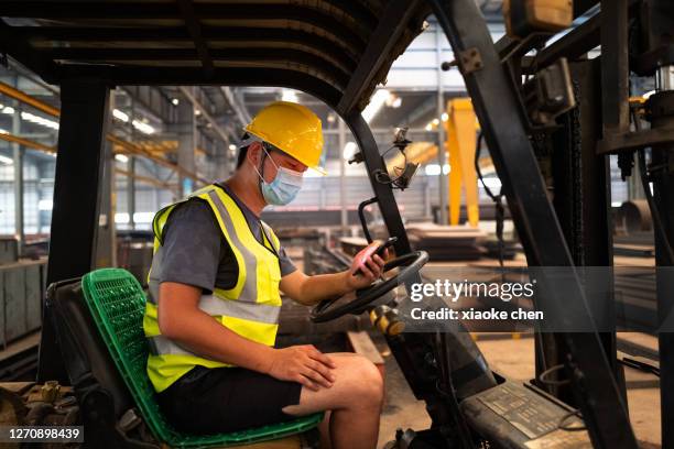 conductor de carretilla elevadora masculina con teléfono móvil - riesgos laborales fotografías e imágenes de stock