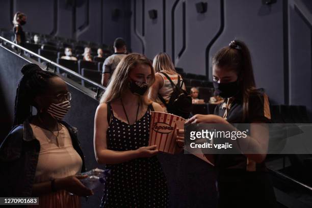 reapertura del cine después de la pandemia de coronavirus - dos mujeres jóvenes que hablan con el cine usher - acomodador cine fotografías e imágenes de stock