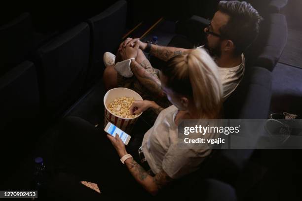 wiedereröffnung kino - glücklich tätowiert paar sehen film - romance film stock-fotos und bilder