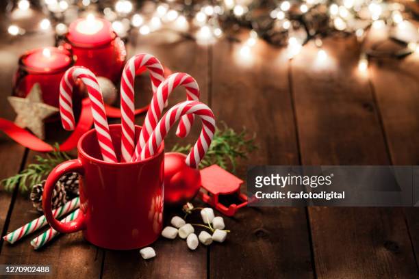 fondos navideños: bastones de caramelo en una taza roja sobre mesa de madera rústica. copiar espacio - candy cane fotografías e imágenes de stock