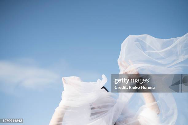 woman with white veil blowing over face - wedding veil photos et images de collection