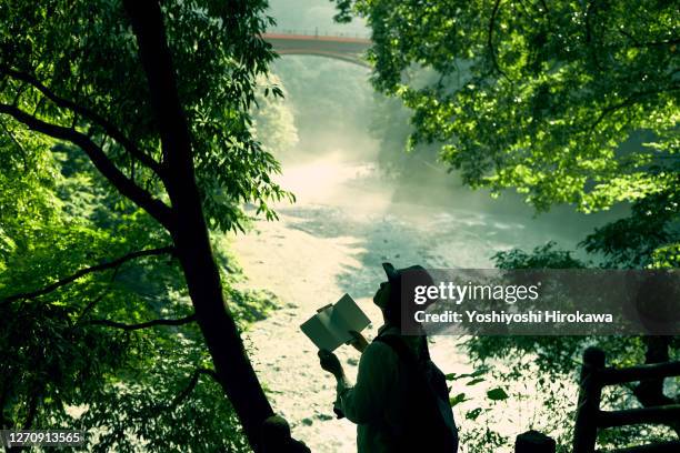 senior woman looking at map by the river flowing from a water source - tokyo map imagens e fotografias de stock