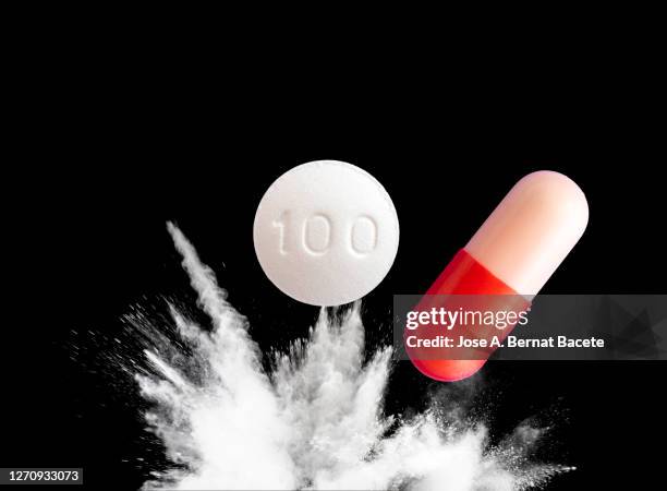 medication pill hits and explodes on the ground on a black background - generikum stock-fotos und bilder