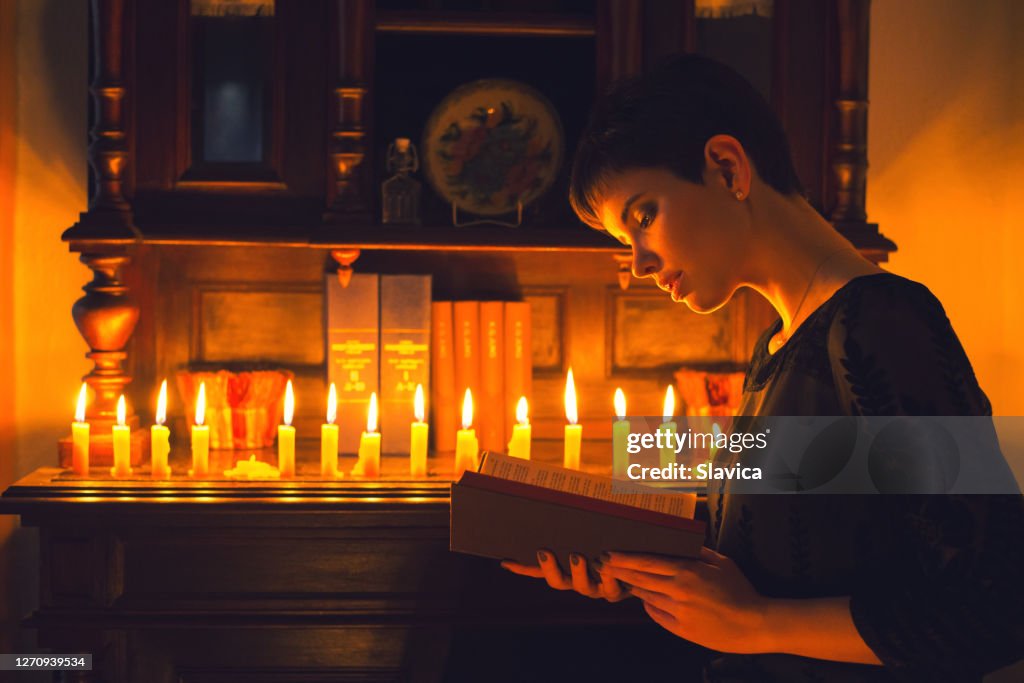 Vrouw die het boek onder het kaarslicht leest