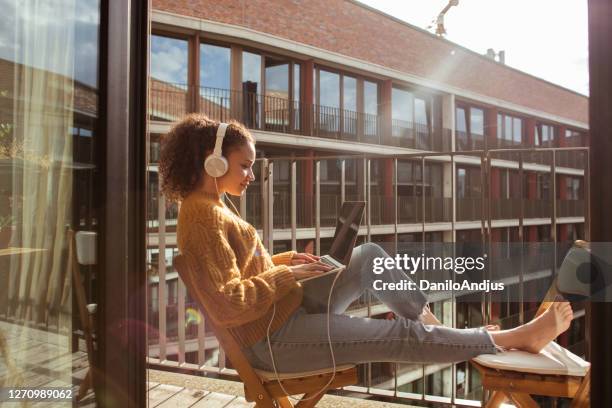 woman is working from home on a laptop - modern balcony stock pictures, royalty-free photos & images