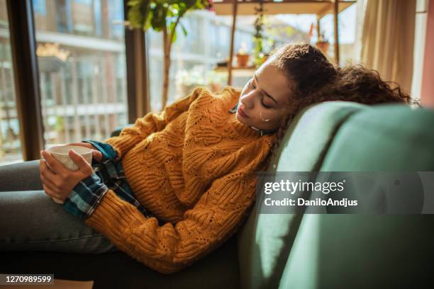 woman is resting on the sofa in her apartment - indecisive woman stock pictures, royalty-free photos & images