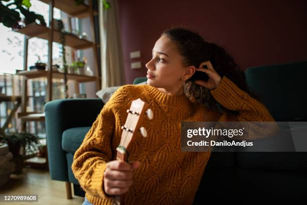 young woman with guitar in her living room - maxim musician stock pictures, royalty-free photos & images