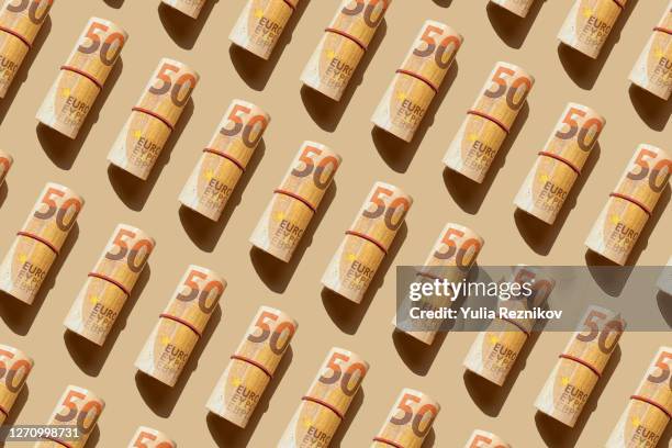 roll of 50 euro banknotes on the beige background - billet de 50 euros photos et images de collection