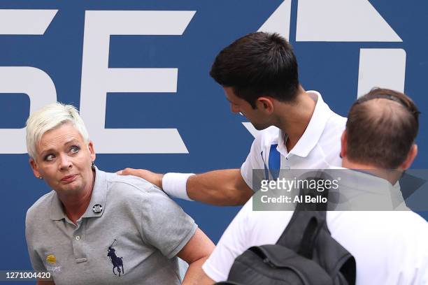 Novak Djokovic of Serbia tends to a line judge Laura Clark who was hit with the ball during his Men's Singles fourth round match against Pablo...