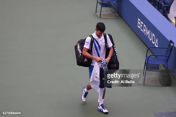 Novak Djokovic of Serbia walks off the court after being defaulted due to inadvertently striking a lineswoman Laura Clark with a ball hit in...