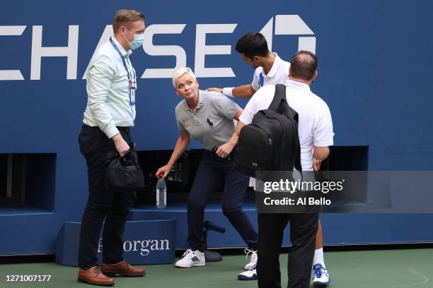Novak Djokovic of Serbia tends to a lineswoman Laura Clark after inadvertently striking her with a ball hit in frustration during his Men's Singles...