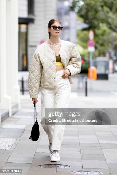 Influencer Jacqueline Zelwis wearing a white Jeans and a beige quilted jacket by Arket, a dark green crop top with a yellow bunch by Hope, white...