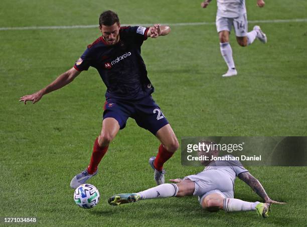 Alexander Buttner of New England Revolution knocks the ball away from Elliot Collier of Chicago Fire at Soldier Field on September 06, 2020 in...